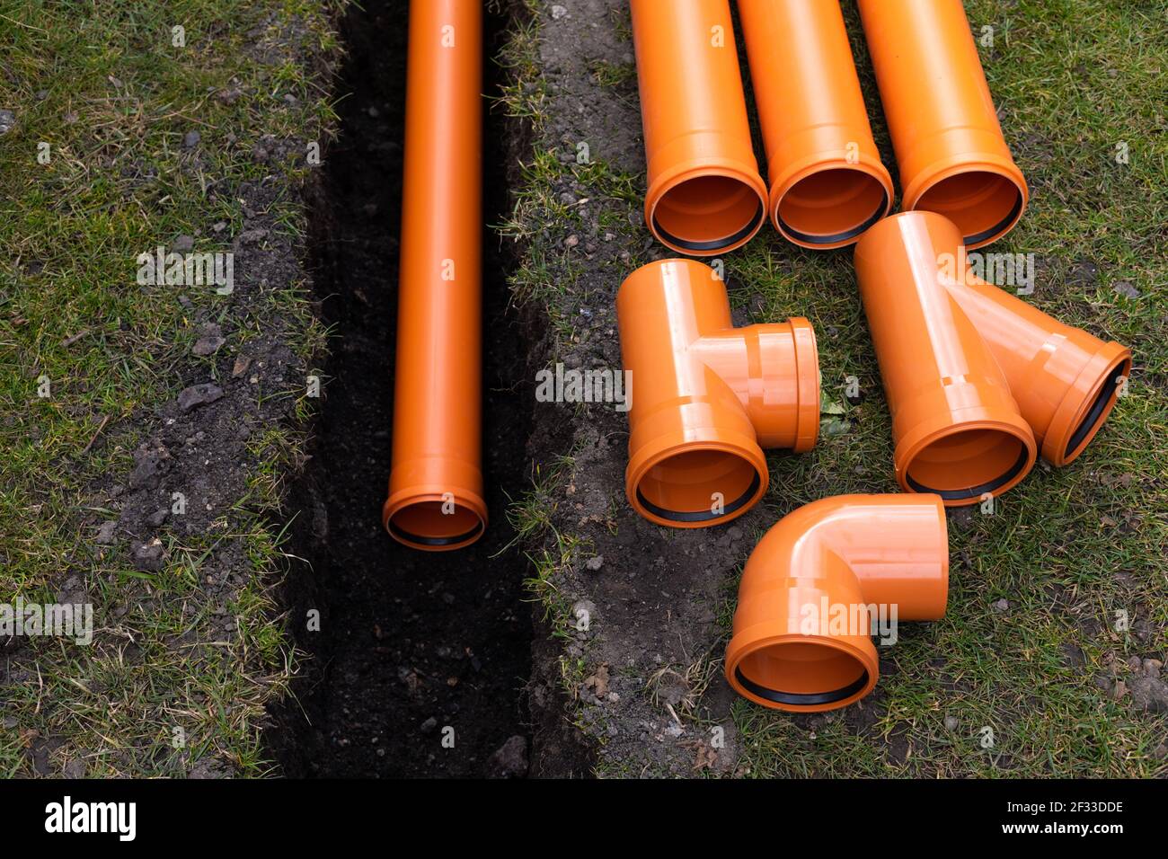 Laying down orange PVC drainage pipes into the ground Stock Photo Alamy