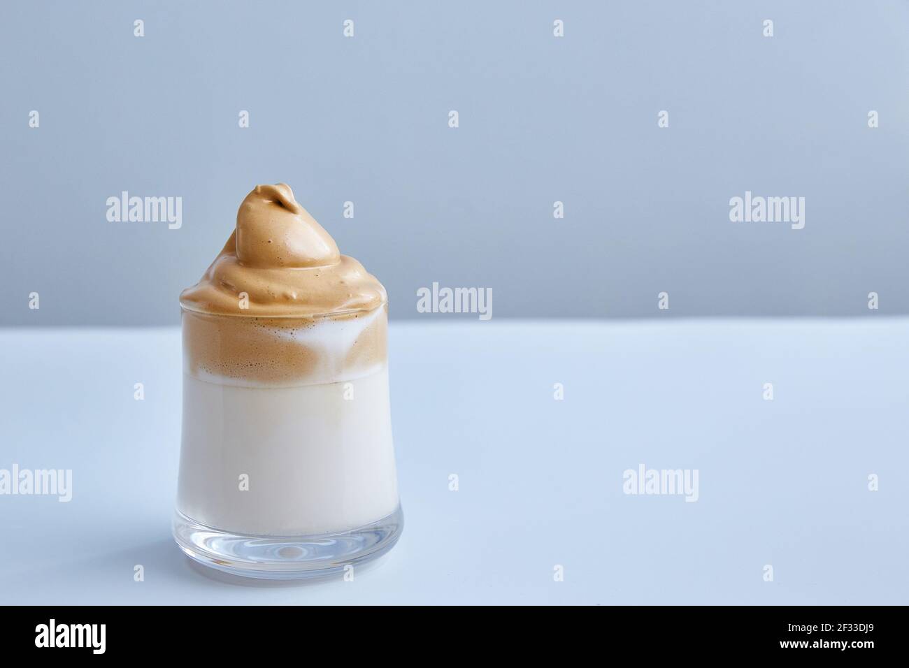 Dalgona-coffee is the fashion trend of this season. Korean traditional cuisine. Milk with coffee and sugar foam. Minimalism, gray background with copy Stock Photo