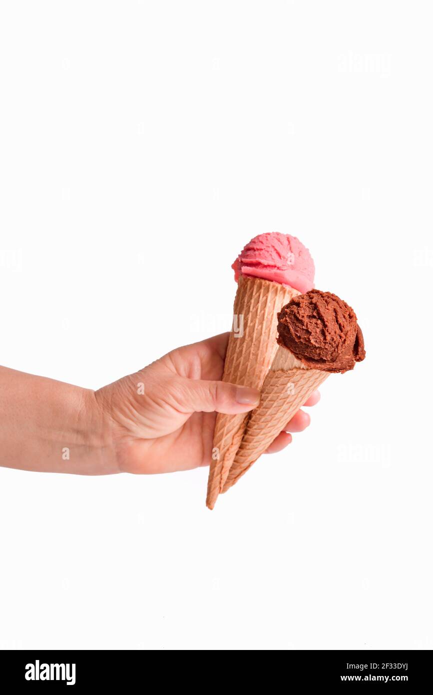 Female hand holding two wafer ice cream cones with chocolate and strawberry ice cream scoops. Selective focus and close up. Ice cream concept. Stock Photo