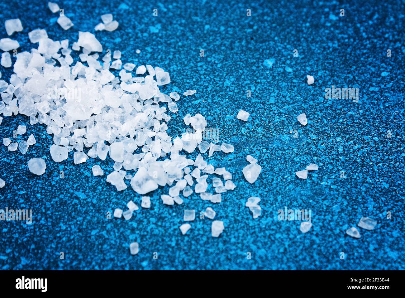 Coarse salt crystals on a blue table. sea salt. Background for