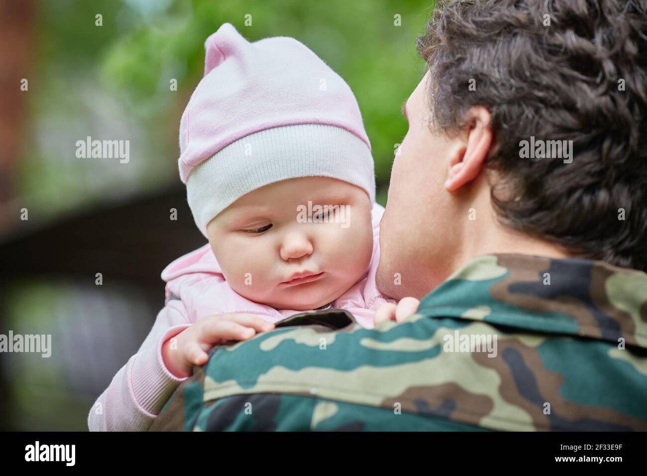 Military Dad goes to War and holds a sad one-year-old Daughter in his arms Stock Photo