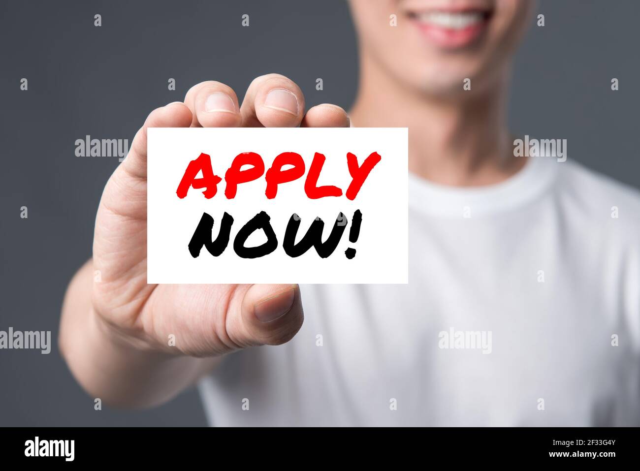 APPLY NOW! message on the card shown by a man Stock Photo