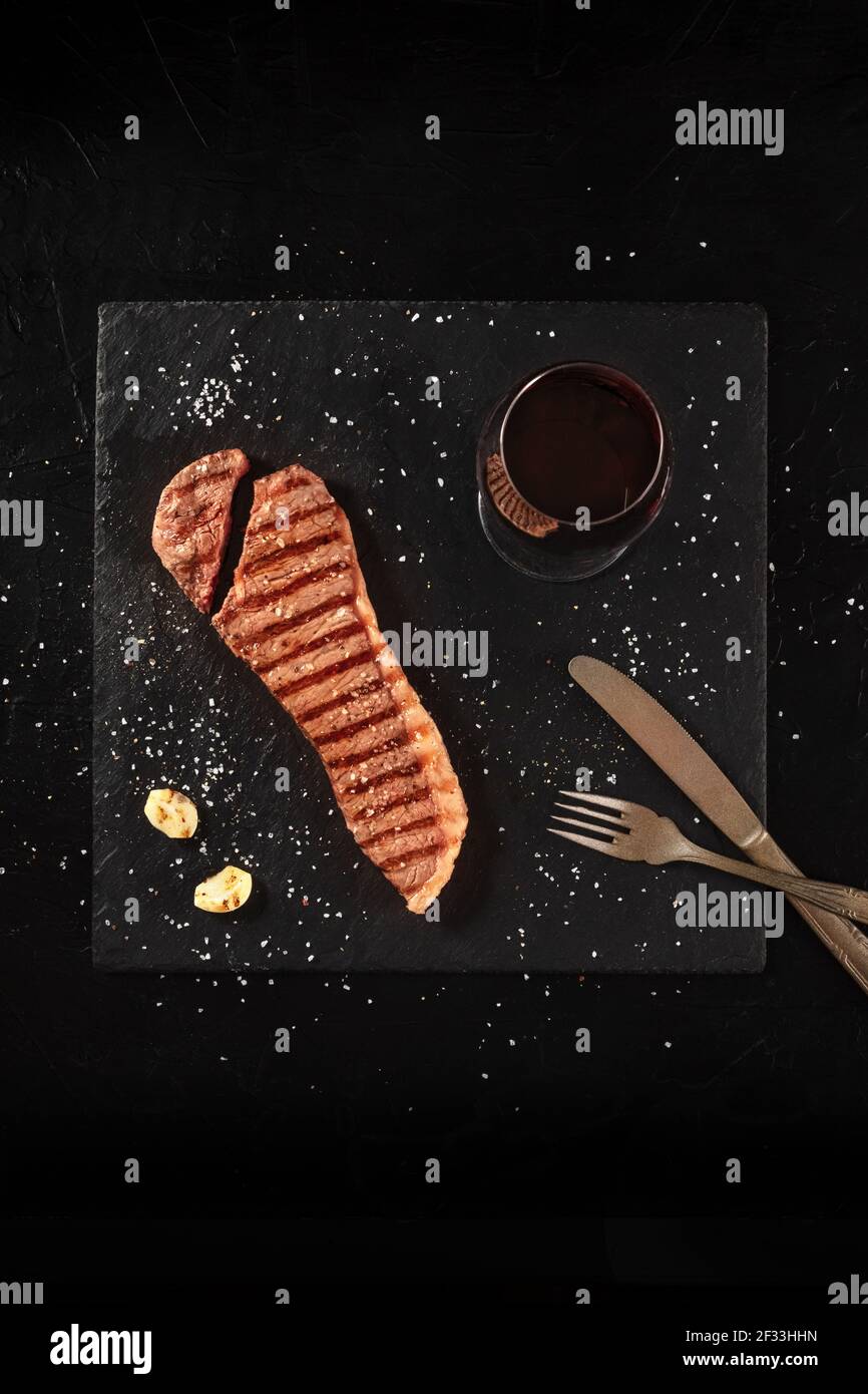 Strip steak, cooked beef cut, shot from the top on black Stock Photo