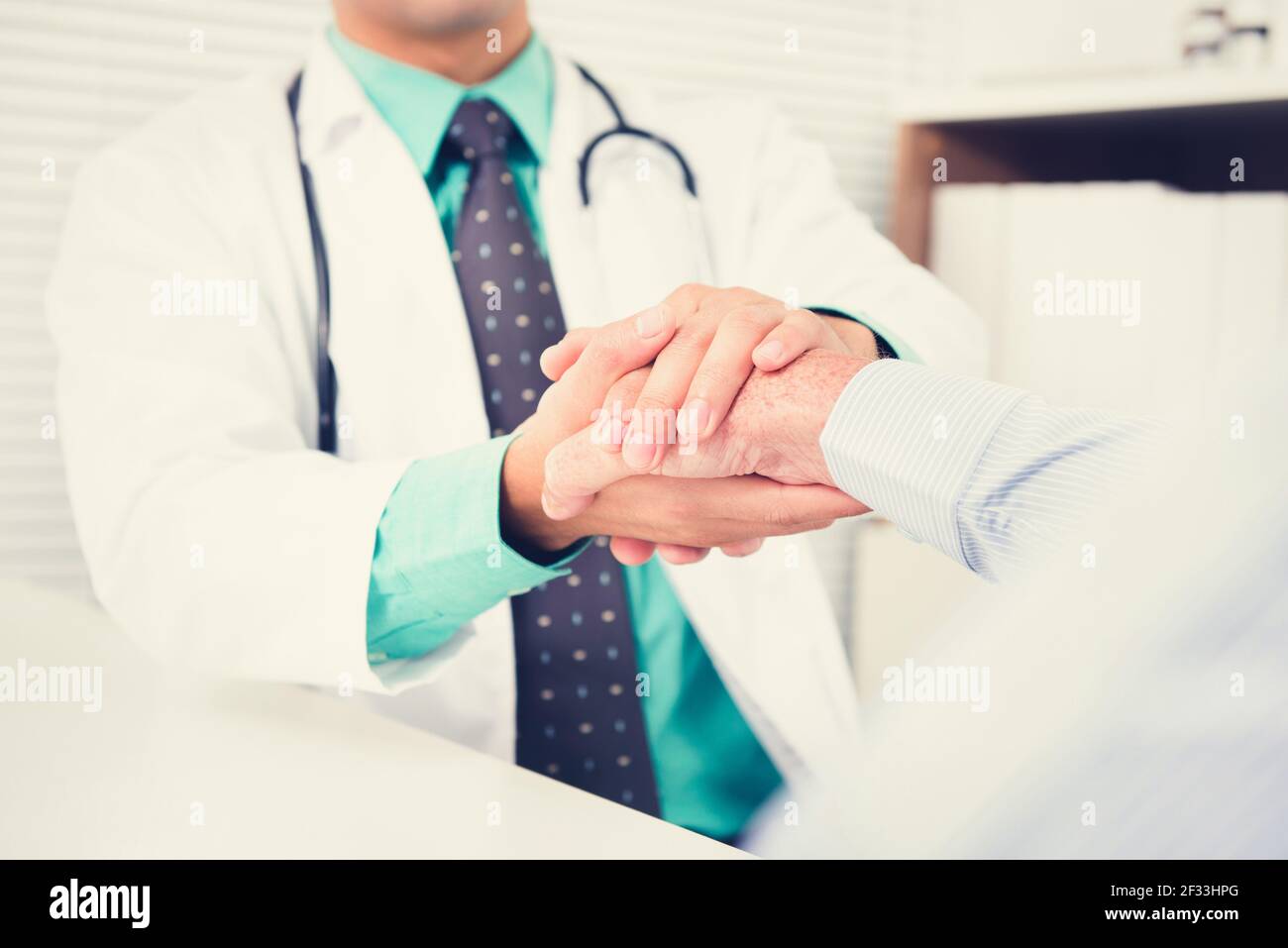 Doctor holding senior male patient hand with care, vintage tone  effect Stock Photo