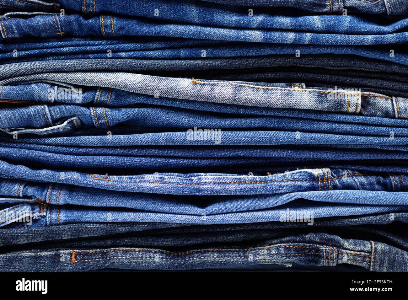 Stack or pile of denim jeans as background texture. Heap of folded ...