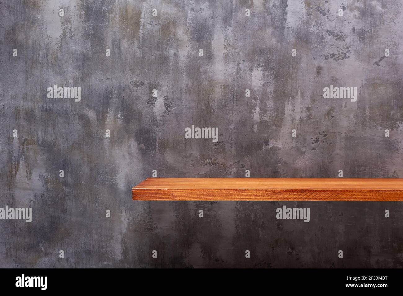 Wooden book shelf at abstract wall background, concrete or putty texture. Front view of tabletop Stock Photo