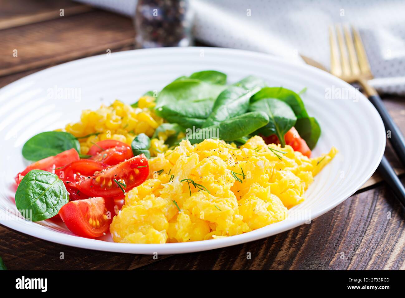 Breakfast. Scrambled eggs with cherry tomatoes, spinach  and corn. Stock Photo