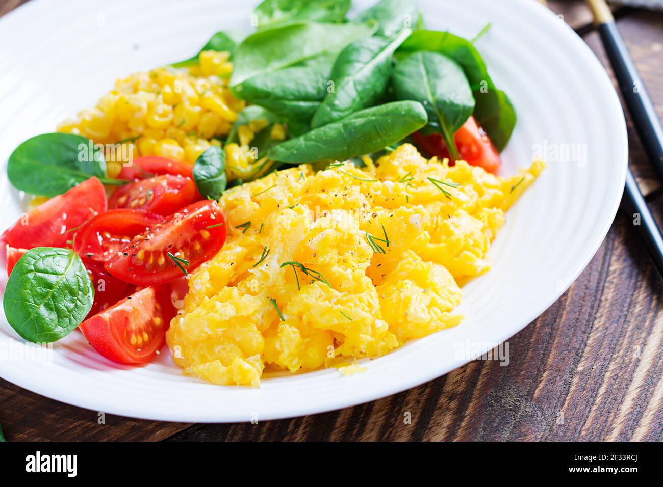 Breakfast. Scrambled eggs with cherry tomatoes, spinach  and corn. Stock Photo