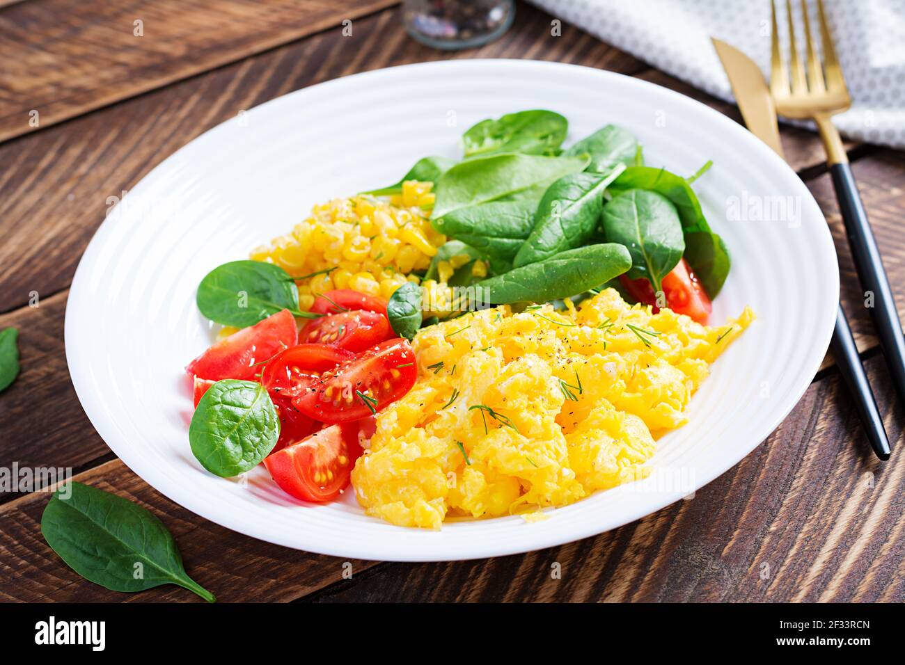 Breakfast. Scrambled eggs with cherry tomatoes, spinach  and corn. Stock Photo