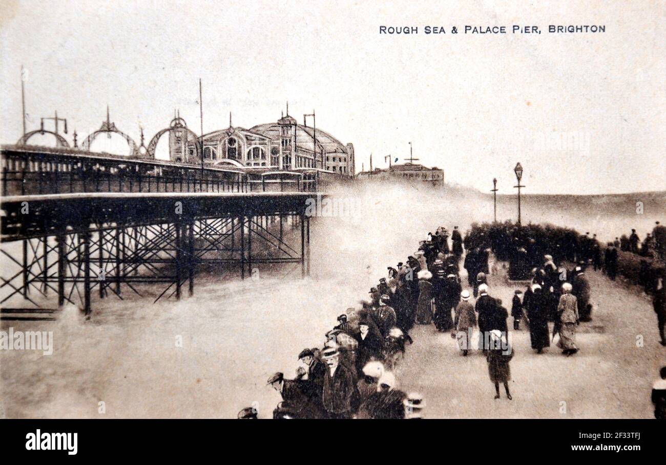 Rough Sea and Palace Pier, Brighton, Sussex, England, United Kingdom. Crowd of people near the sea wall and the stormy waves. Antique postcard. Publisher unknown. Stock Photo