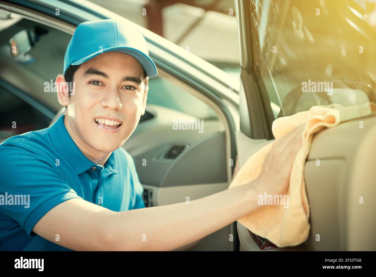 Smiling auto service staff cleaning car door car detailing and