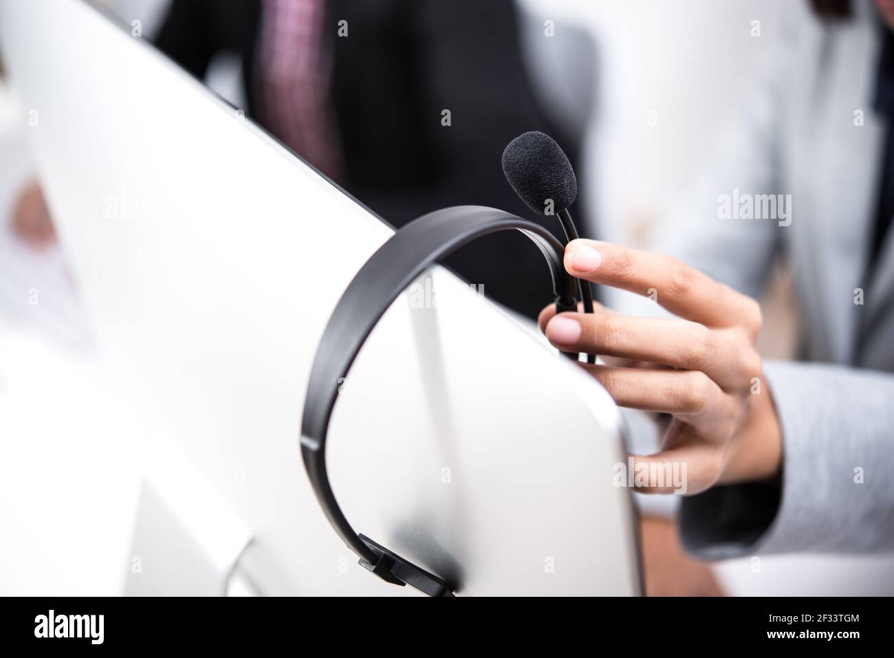 Hand picking up headphone that hanging on computer screen Stock Photo