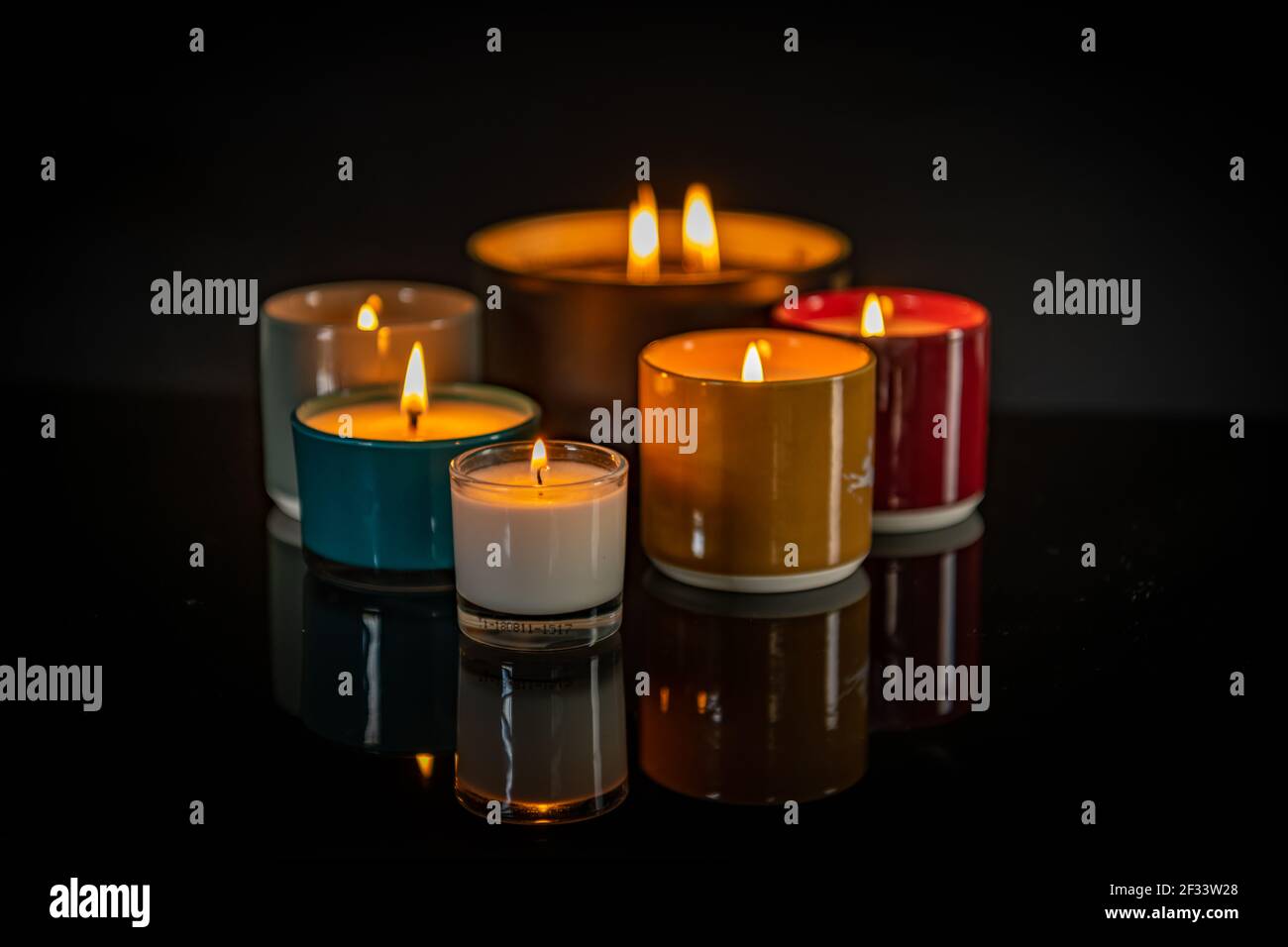 Scented candles lit and reflecting in a shiny black surface Stock Photo Alamy