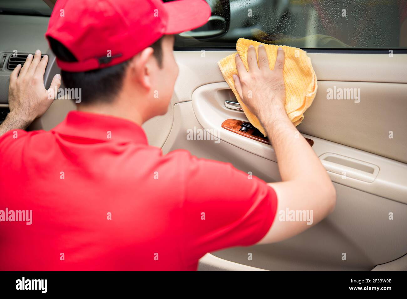 A man cleaning car door panel with microfiber cloth - auto cleaning service concept Stock Photo