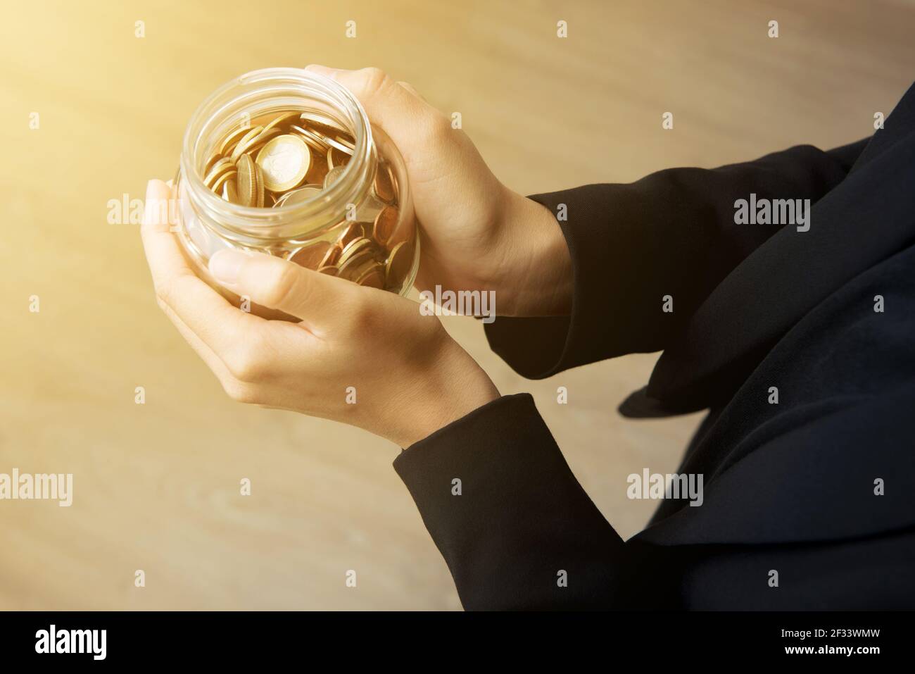 Businesswoman hands holding glass jar with coins Stock Photo