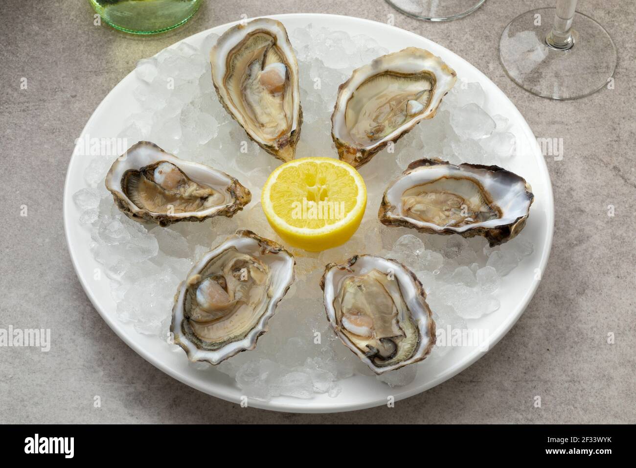 Plate with fresh raw open Pacific oysters, Japanese oyster on ice as appetizer or snack Stock Photo