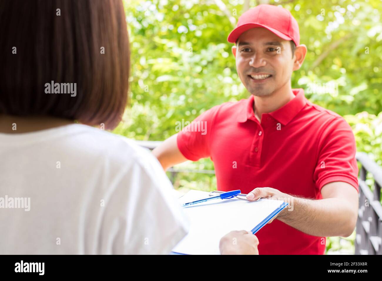 Delivery man giving clipboard to a woman to sign Stock Photo