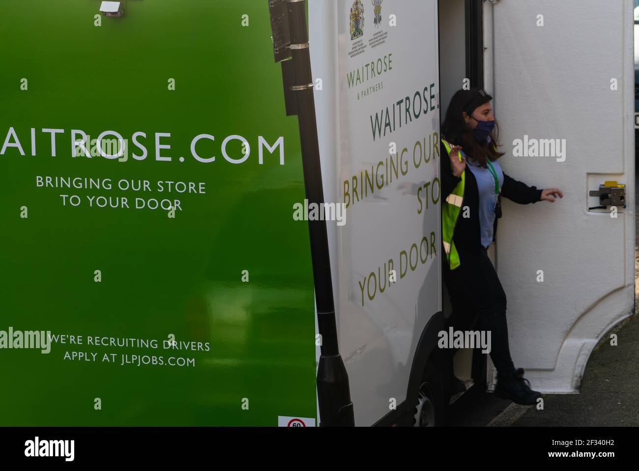 A Waitrose supermarket home grocery delivery showing the company's signs and logo on the vehicle and the delivery driver. Stock Photo