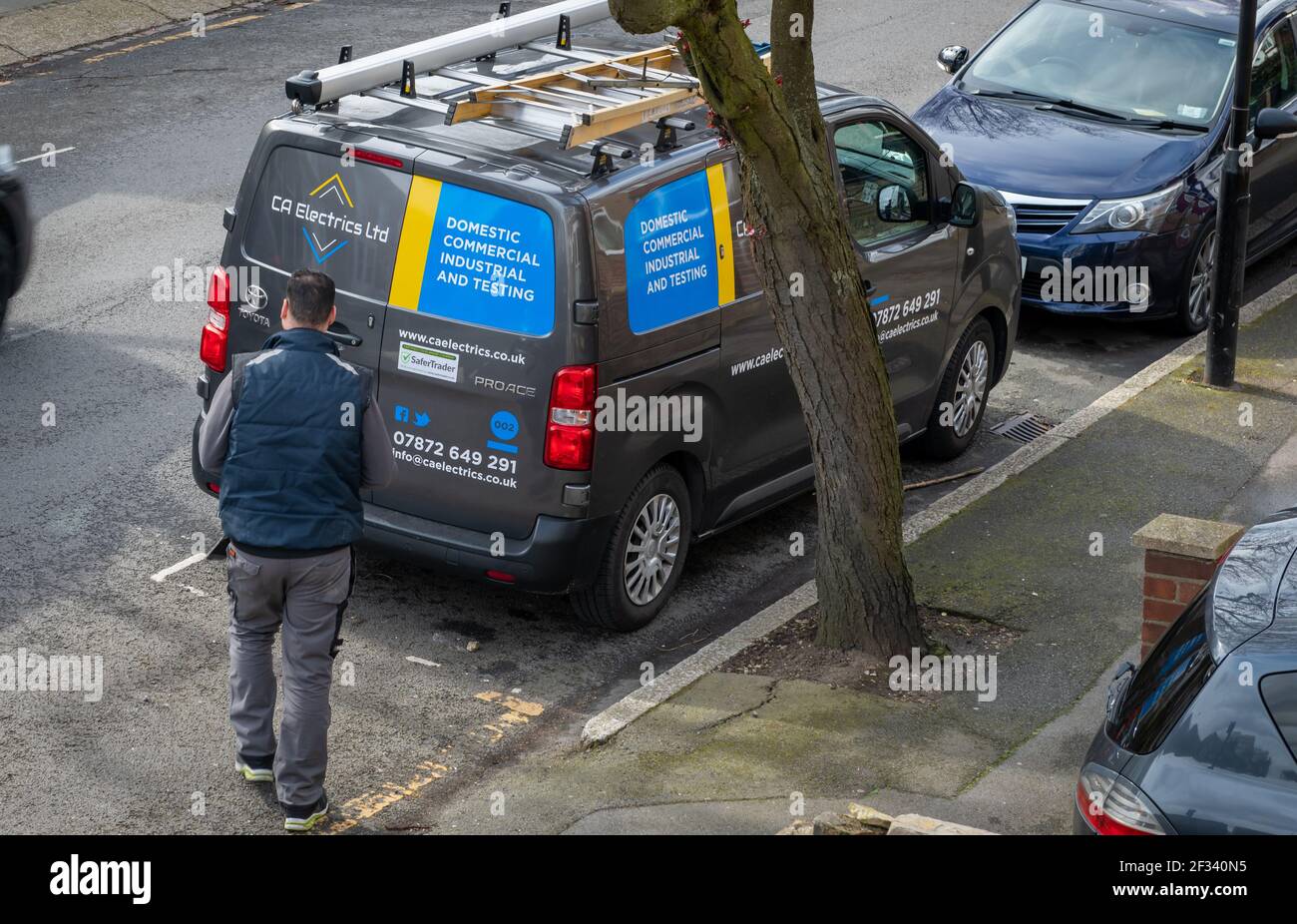 The vehicle of a electric service company and the electrician on call out to carry out electrical work. Stock Photo