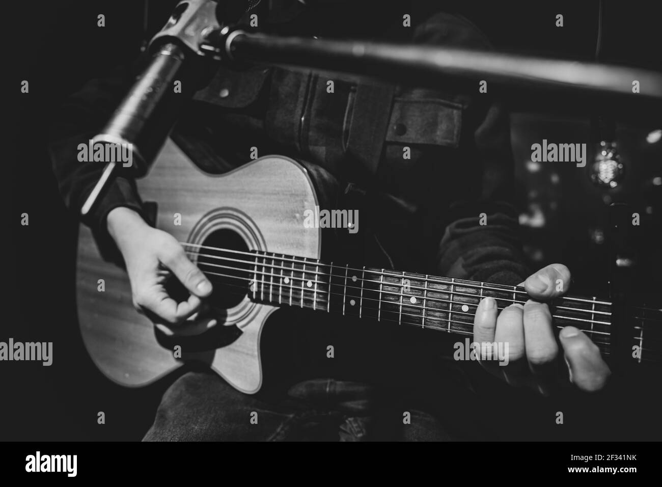 The guitarist plays an acoustic guitar with a capo in front of a