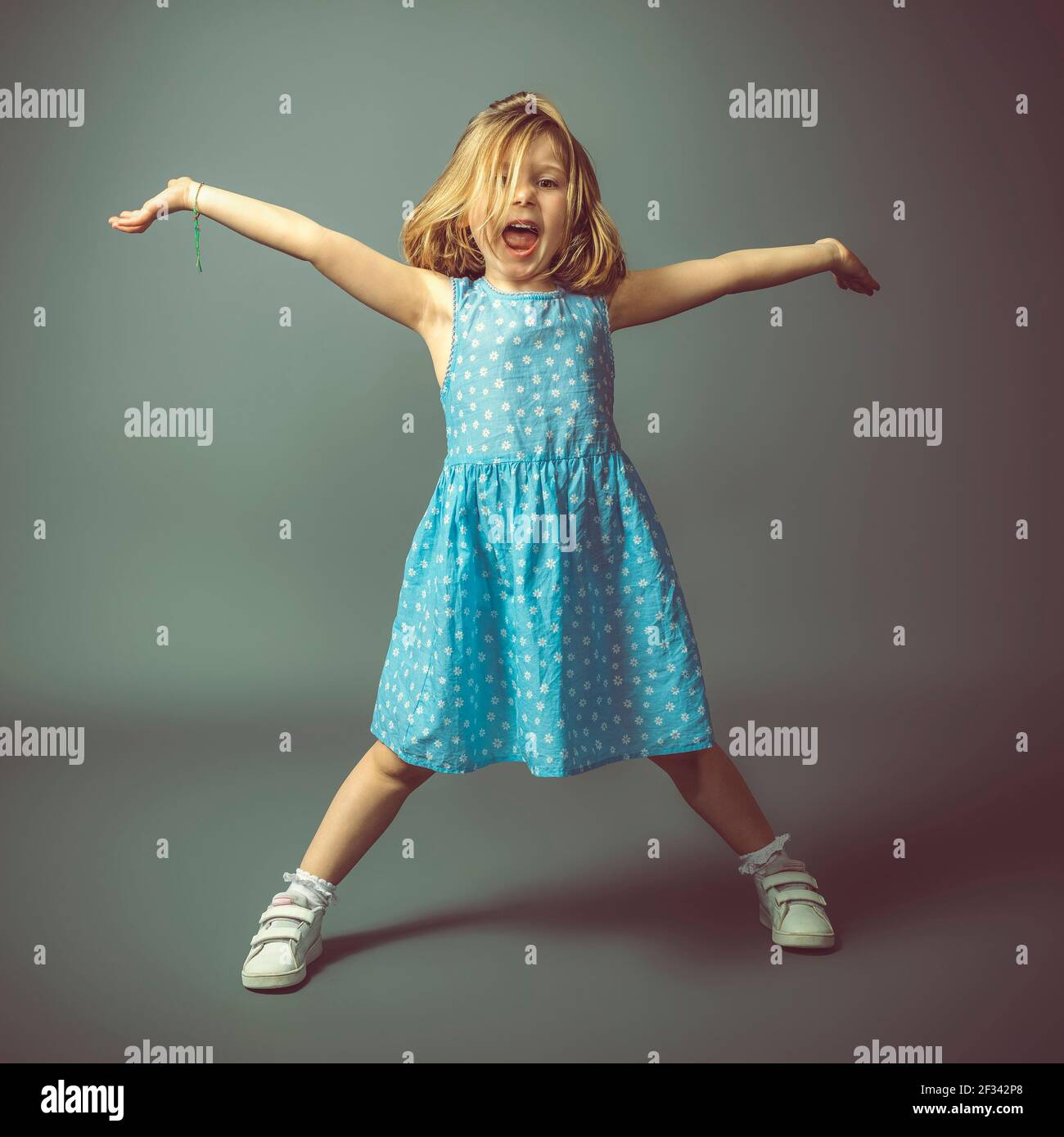 happy little girl with open arms on gray background, studio photo. Stock Photo