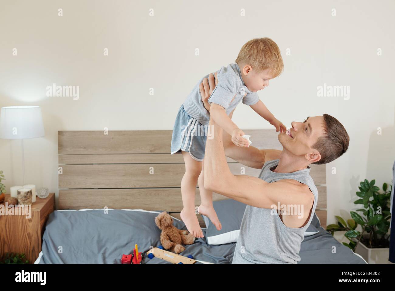 Happy father sitting on bed and playing with his child in the bedroom Stock Photo