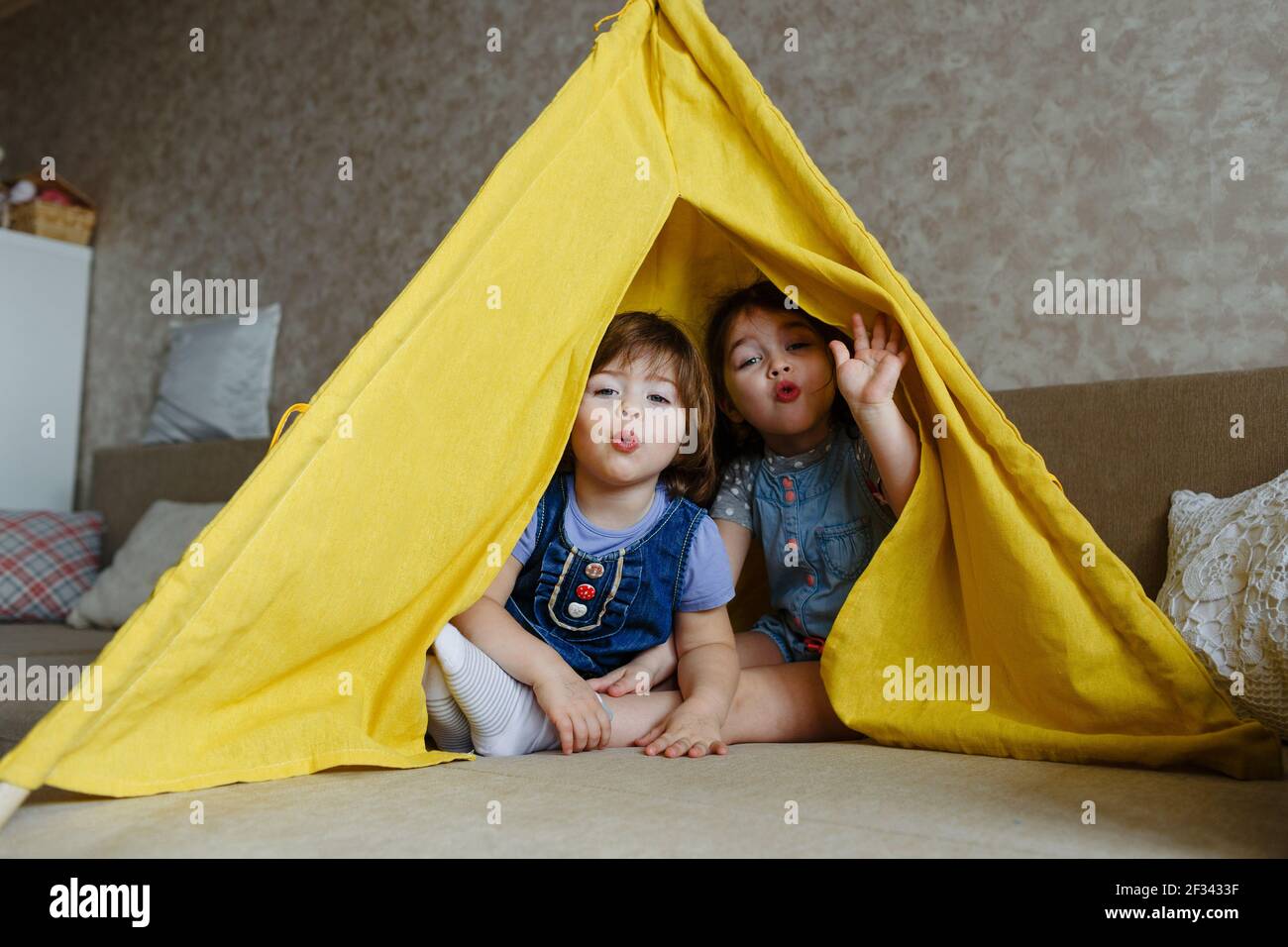 two little girls play at home in yellow in a teepee Stock Photo - Alamy