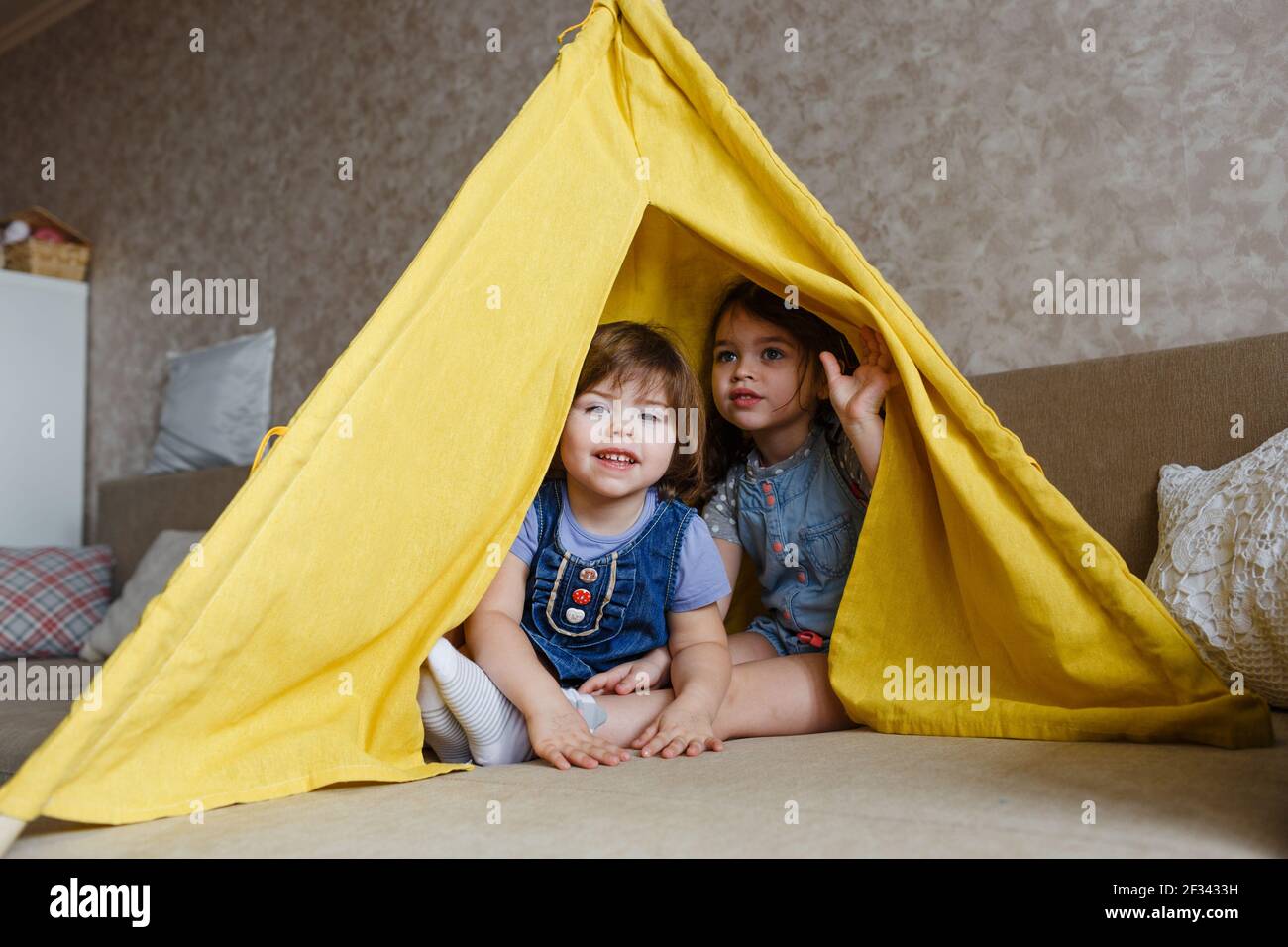two little girls play at home in yellow in a teepee Stock Photo - Alamy