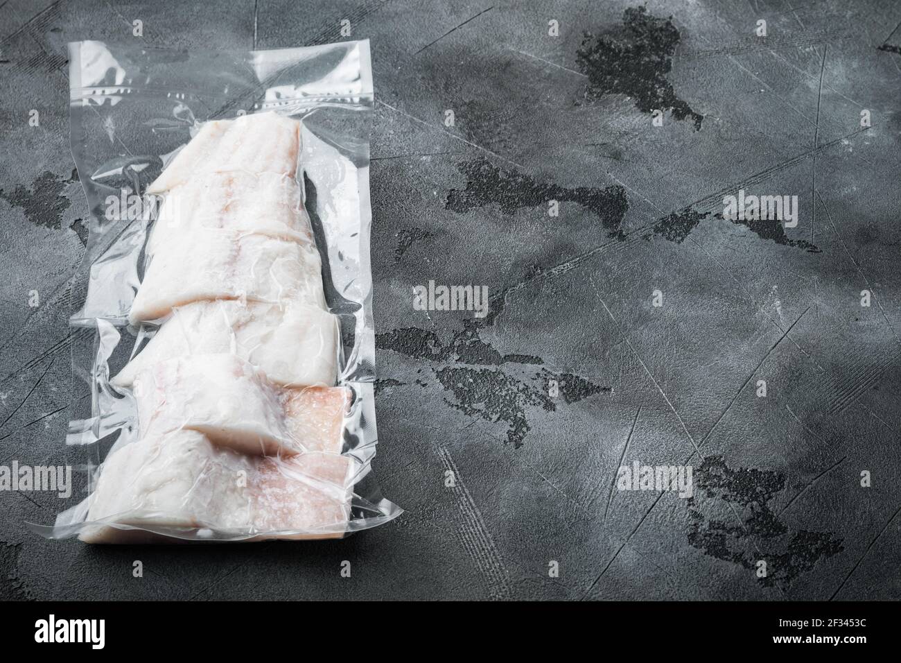 Haddock white fish fillet in plastic market package, on gray background with copy space for text