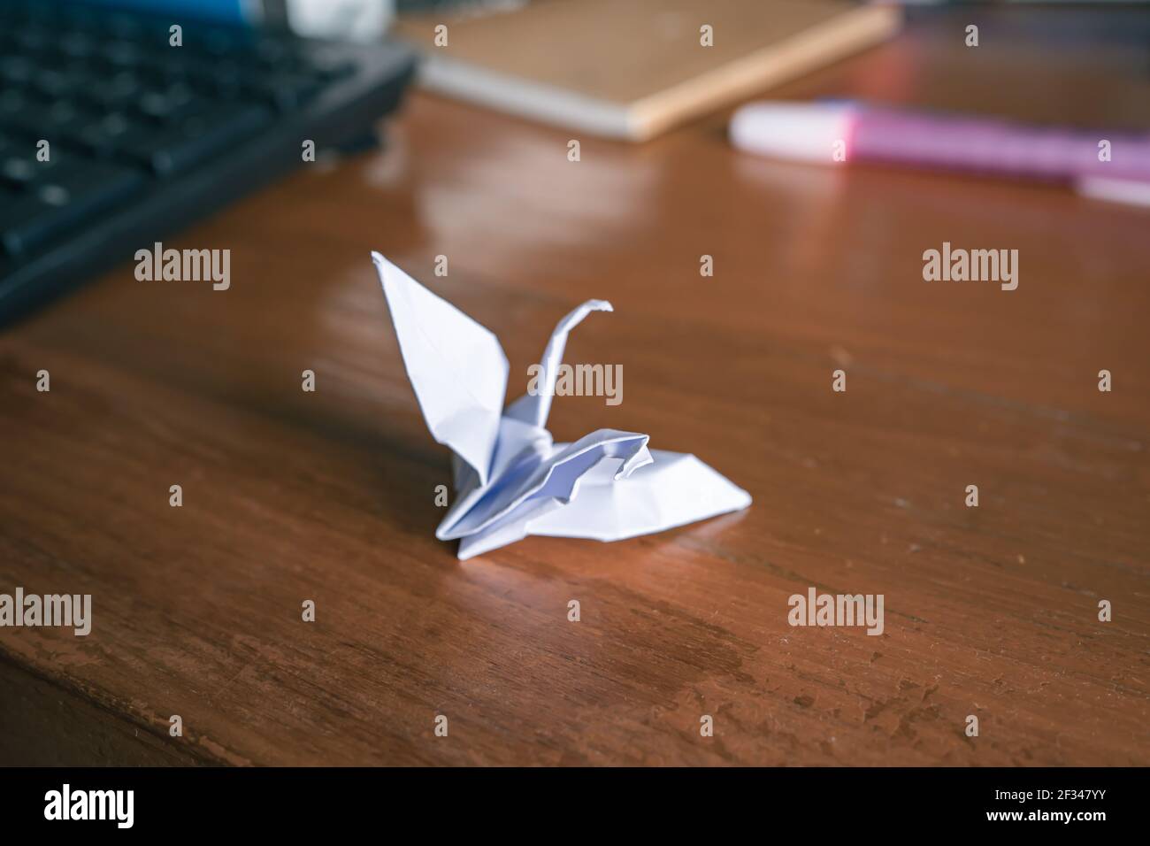 Mental illness concept. Damaged origami paper crane on wooden table. Stock Photo