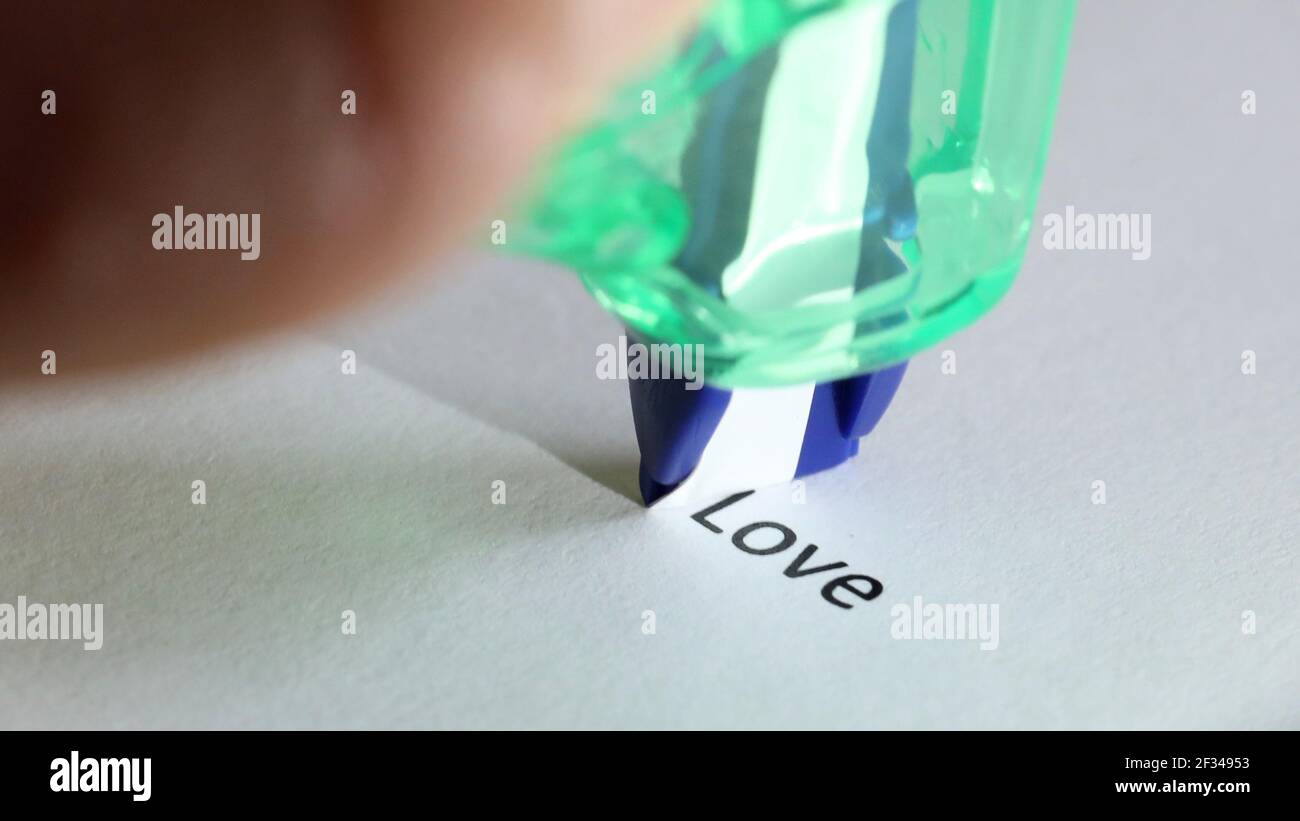 The word love about to be removed, covered up, deleted or erased by a white correction tape pen. Stock Photo