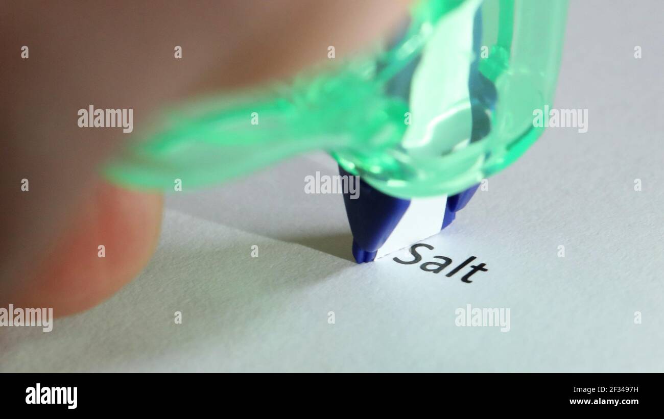 Close up of a correction tape about to cover up and erase the typed word salt. Heathy diet heart health and eating habits Stock Photo