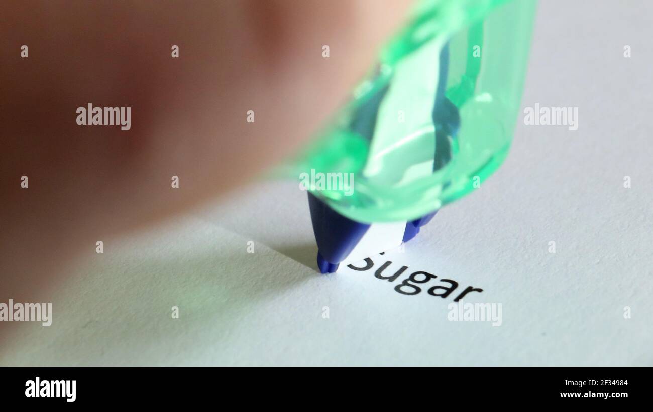 cutting out or removing sugar from your diet concept. The word sugar is partially erased or covered by correction tape. Stock Photo