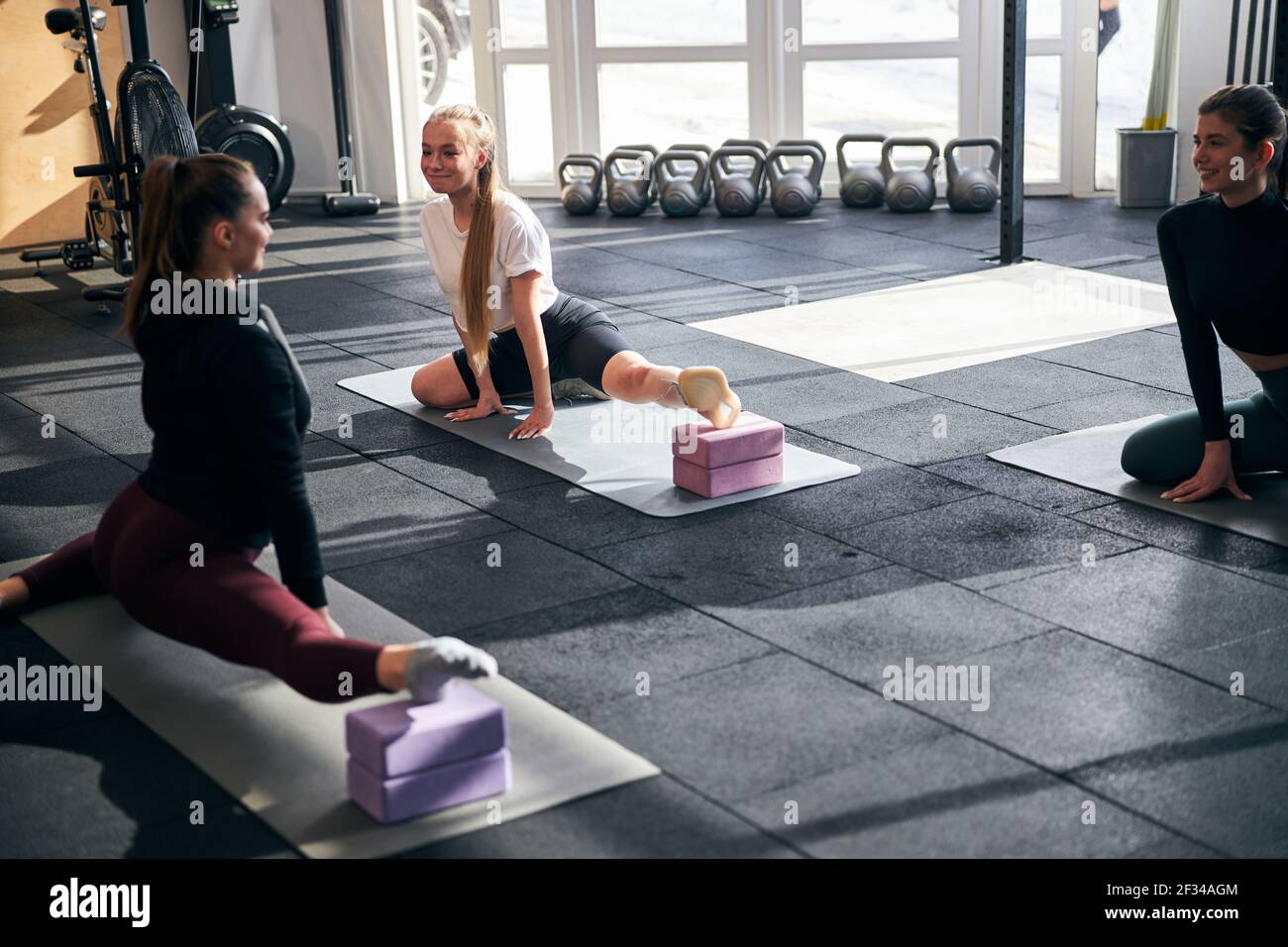 Lovely woman and her friends using yoga blocks for stretching Stock