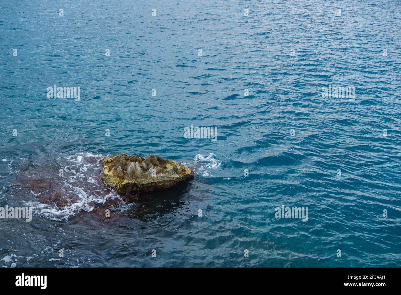 Reef or stone rock that appeared at low tide. Dark blue sea is on background Stock Photo