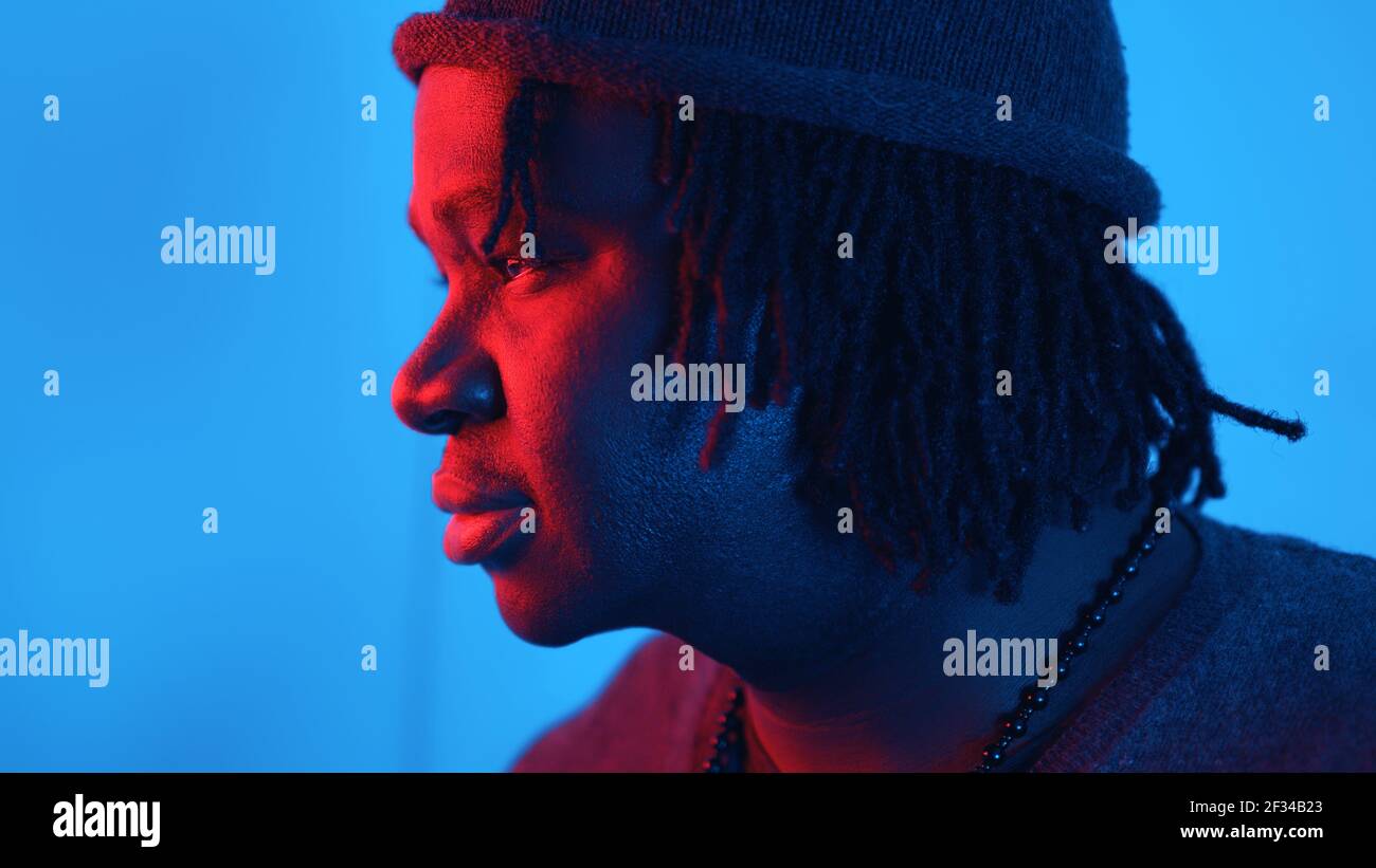 Pensive young african american black man lit with red and blue light. Close up face expression. High quality photo Stock Photo