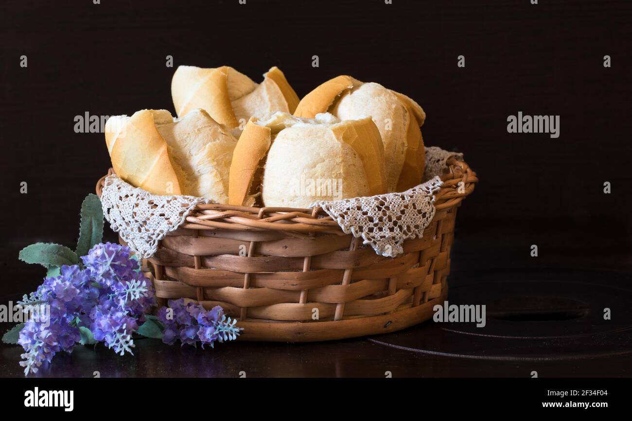 A basket of freshly baked white wheat bread next to flowers Stock Photo