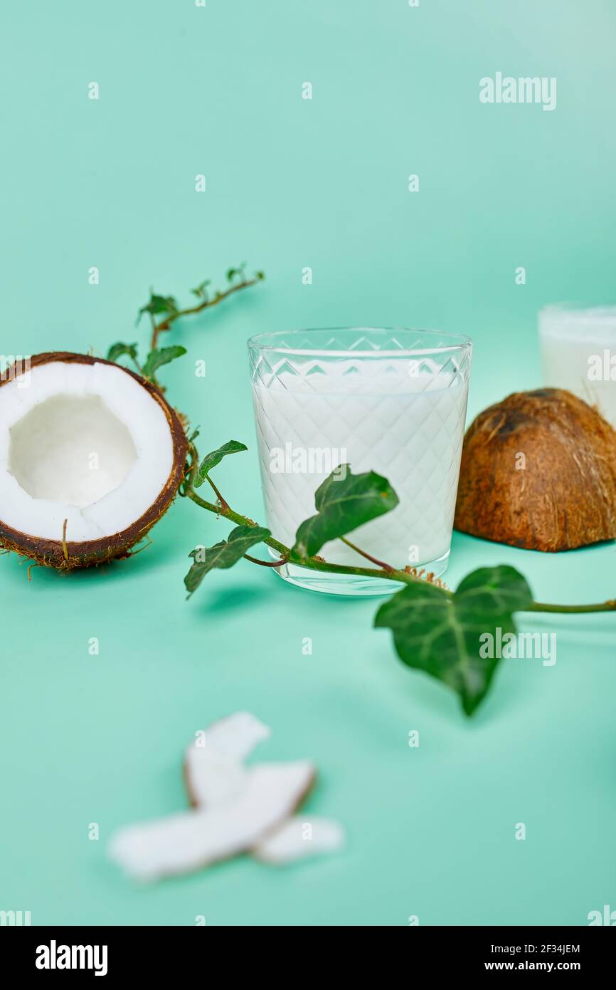 Fresh healthy coconut milk in a glass on blue background, Alternative