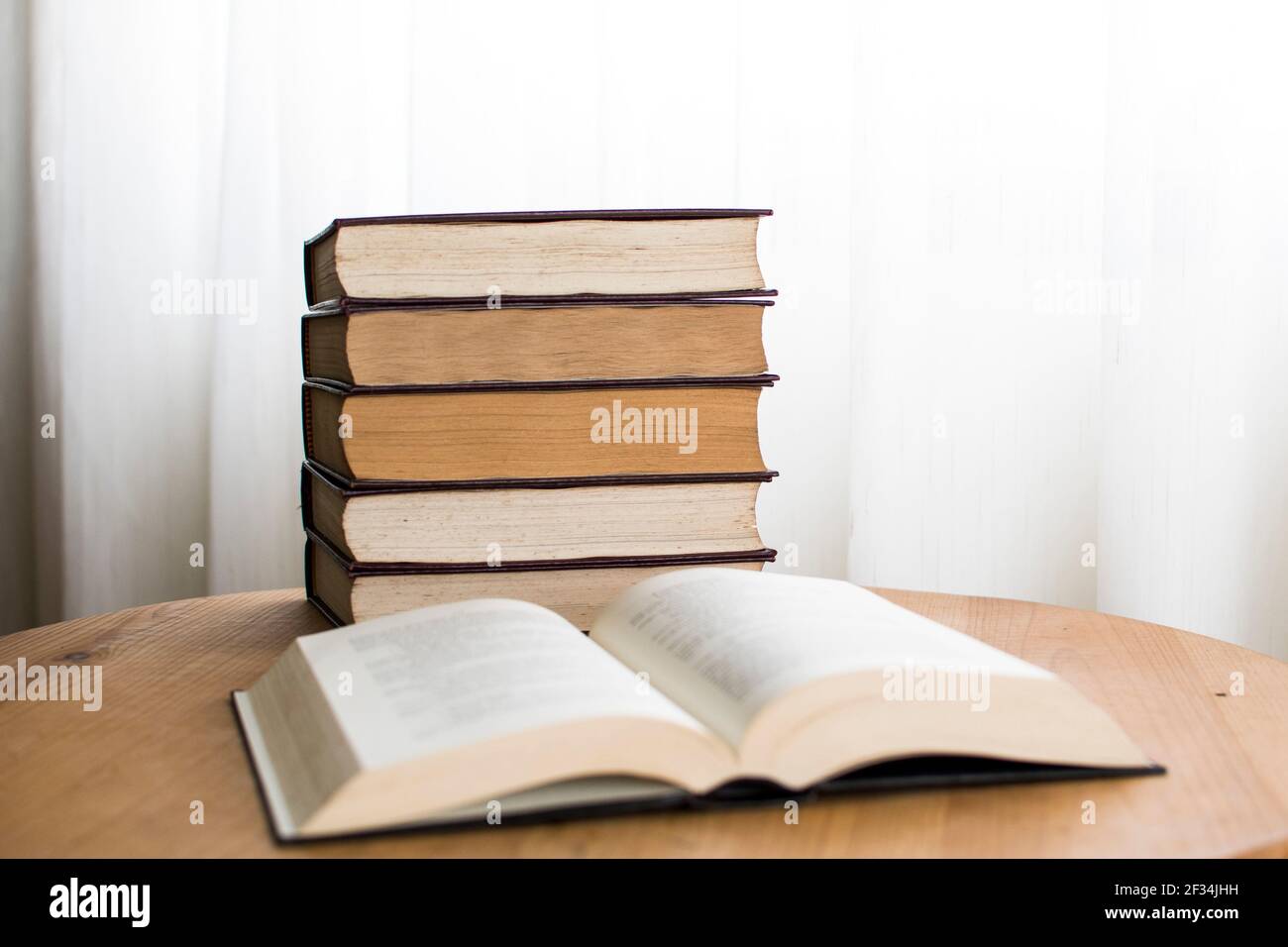 Hard cover books stacked on top of each other on top of a desk, studying material Stock Photo