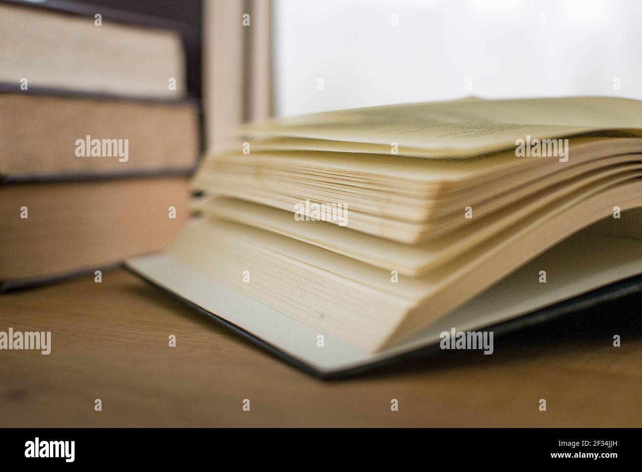 Hard cover books stacked on top of each other on top of a desk, studying material Stock Photo