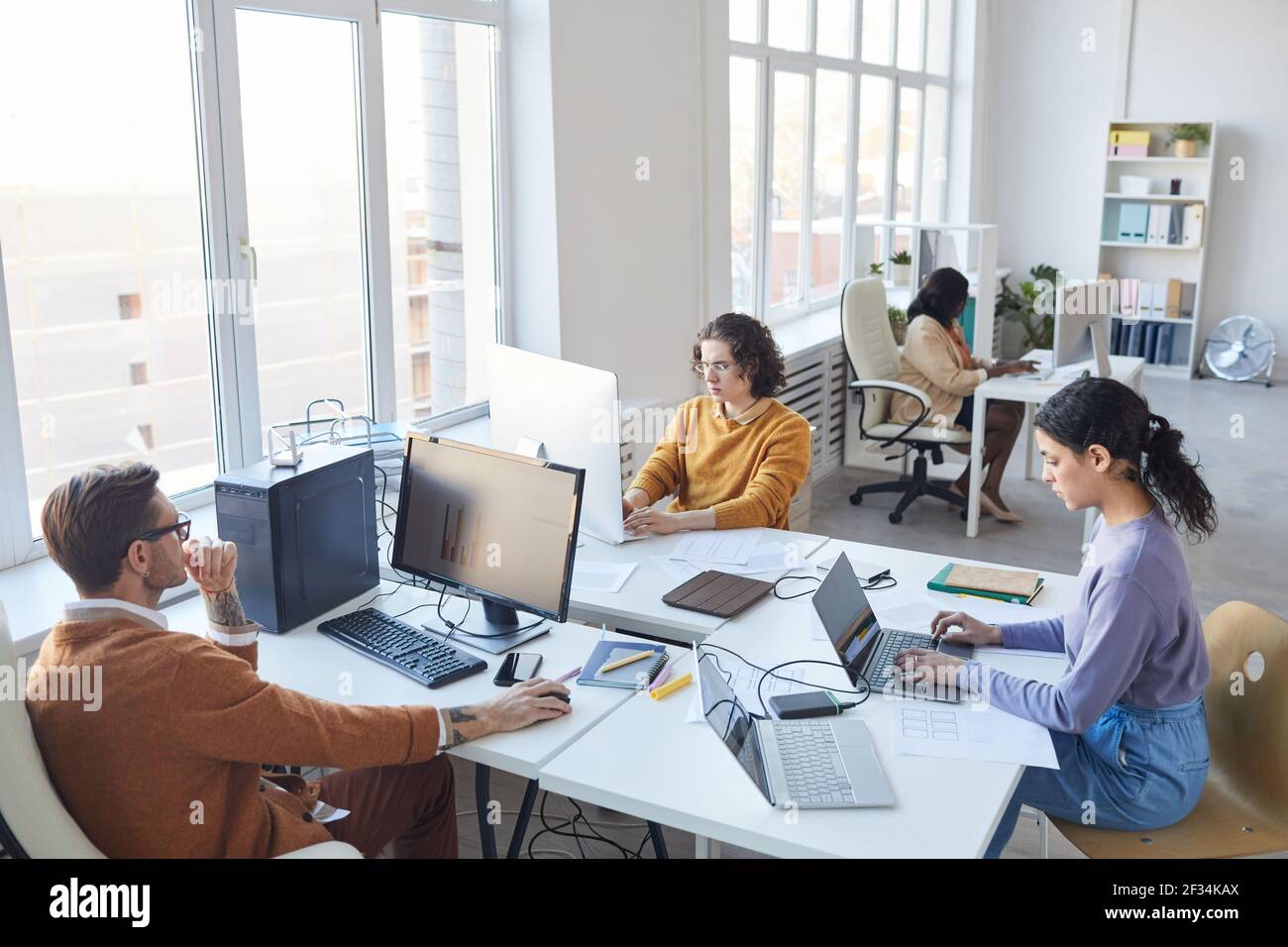 High angle view at diverse software development team using computers at workplace in white office interior, copy space Stock Photo