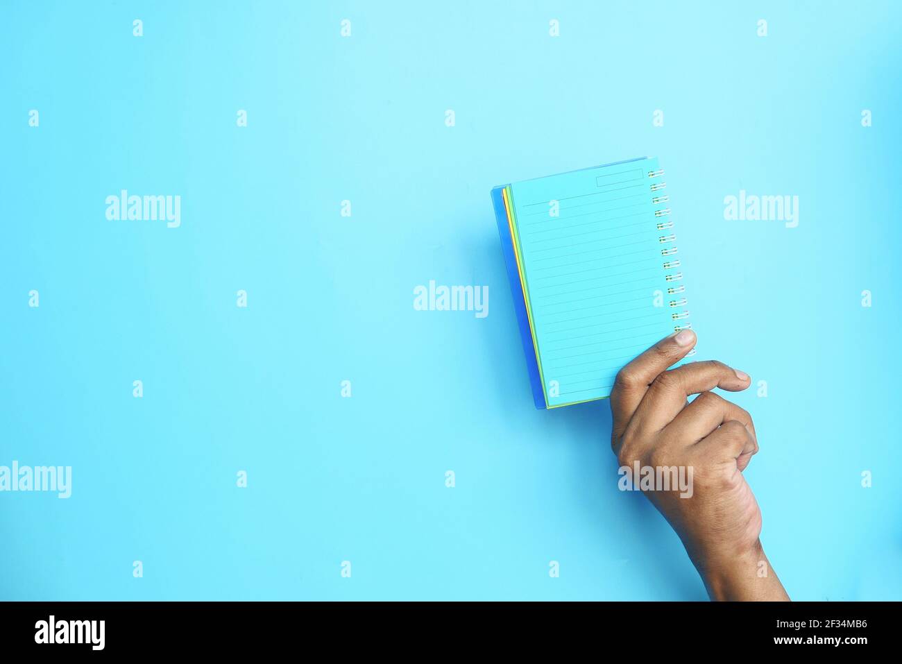 holding open notepad on blue background  Stock Photo