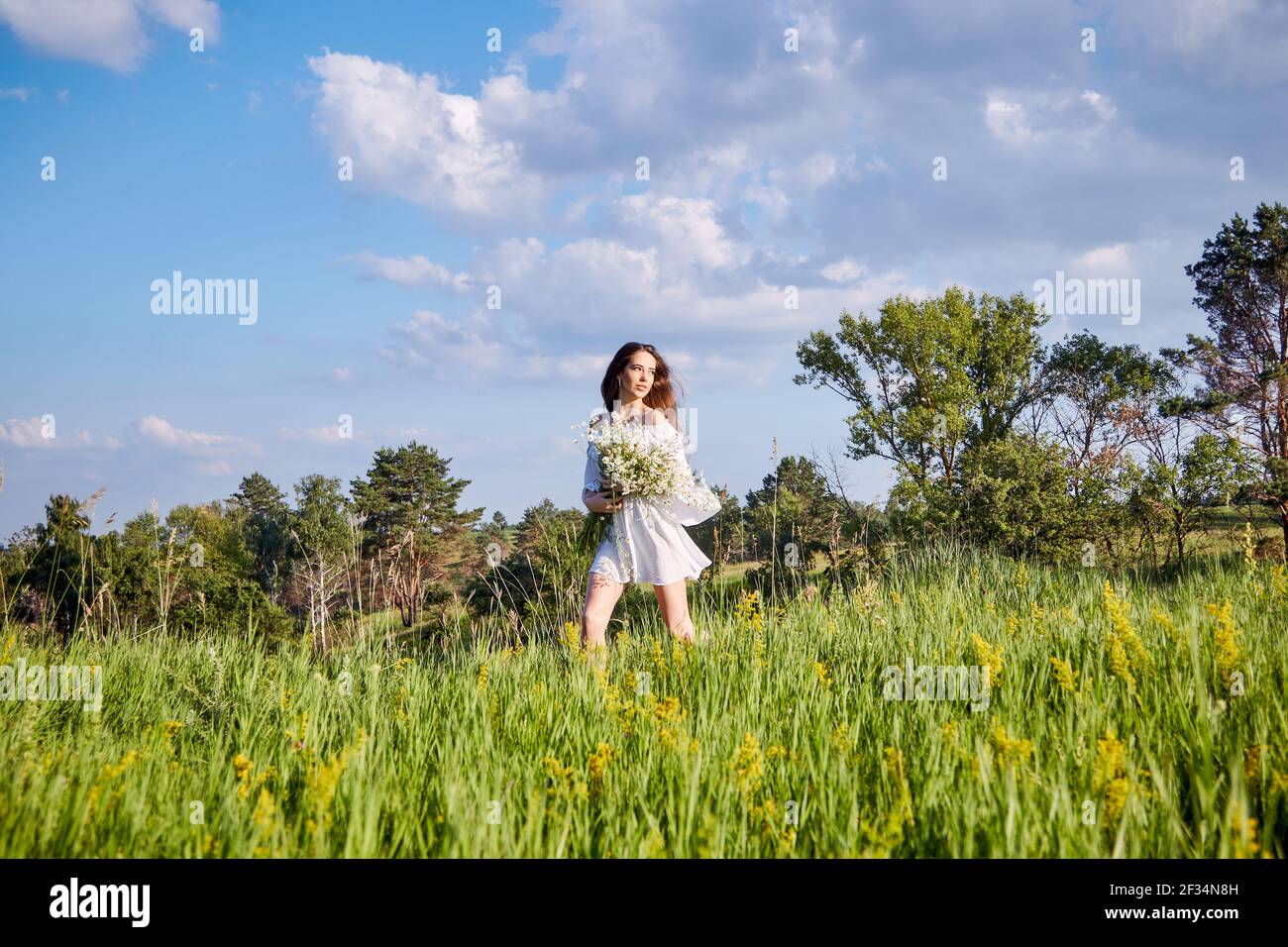 a girl in a white dress with a bouquet of flowers is walking in the ...