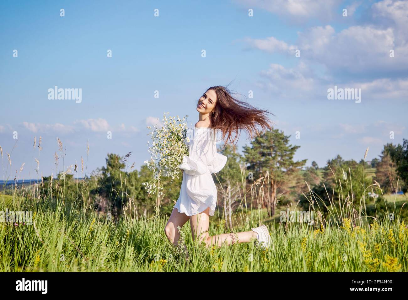 a girl in a white dress with a bouquet of flowers is walking in the ...