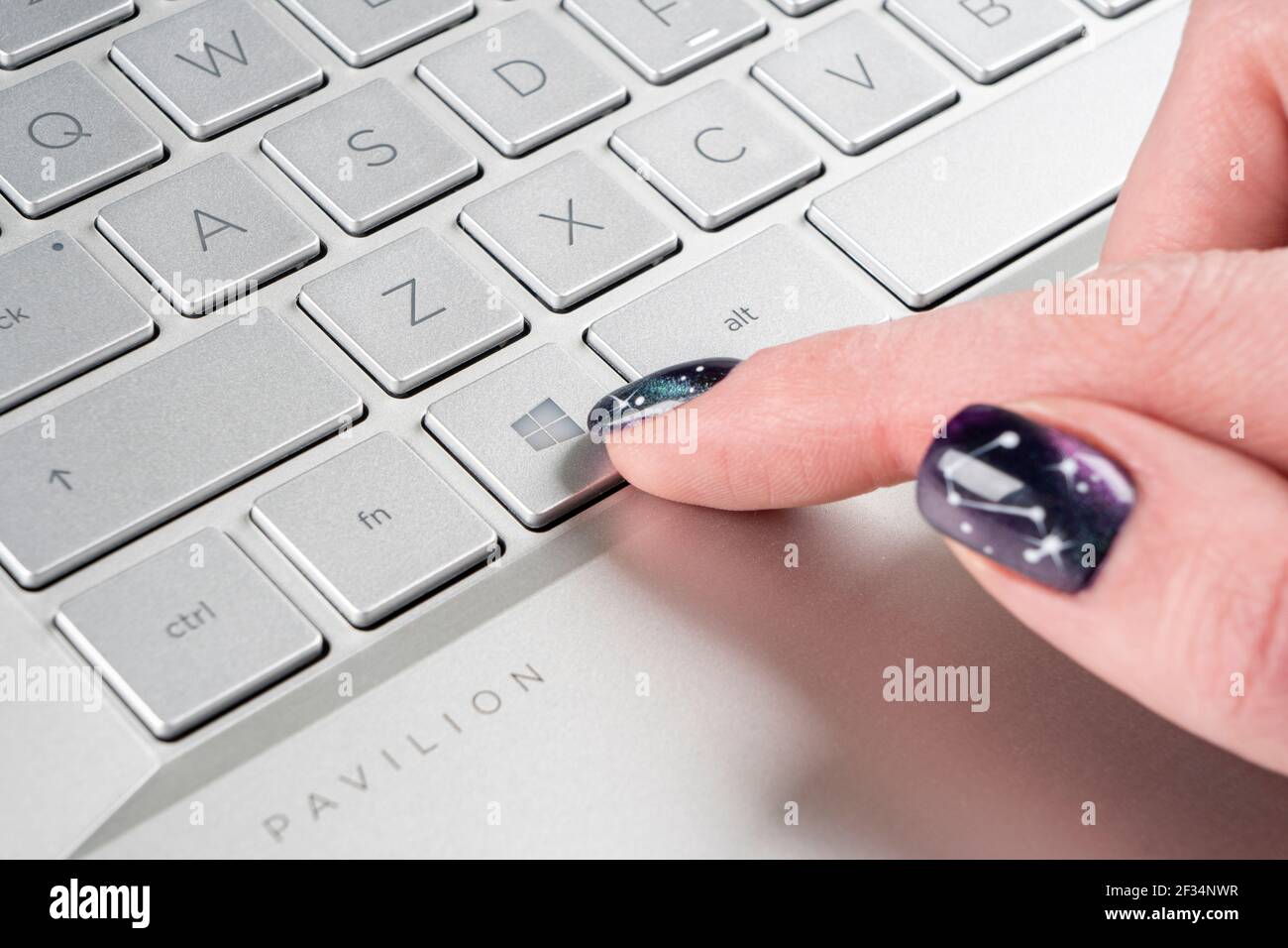Sankt-petersburg, Russia, March 9, 2021: Laptop user finger pressing Windows icon key button on Microsoft Windows keyboard. Woman hand pressing Micros Stock Photo