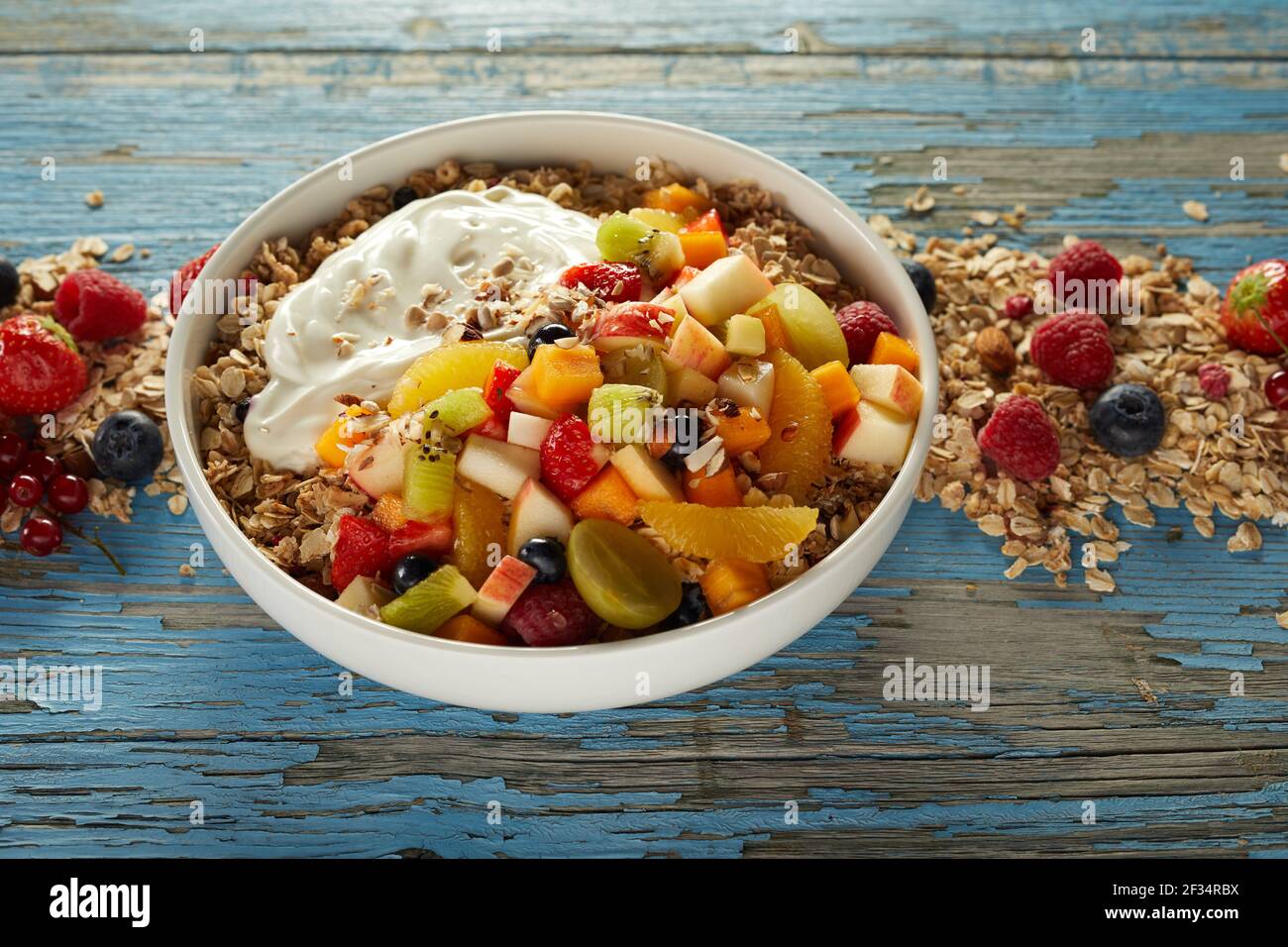 High angle of bowl of muesli served on wooden table with various berries and fruits for healthy nutritious breakfast Stock Photo