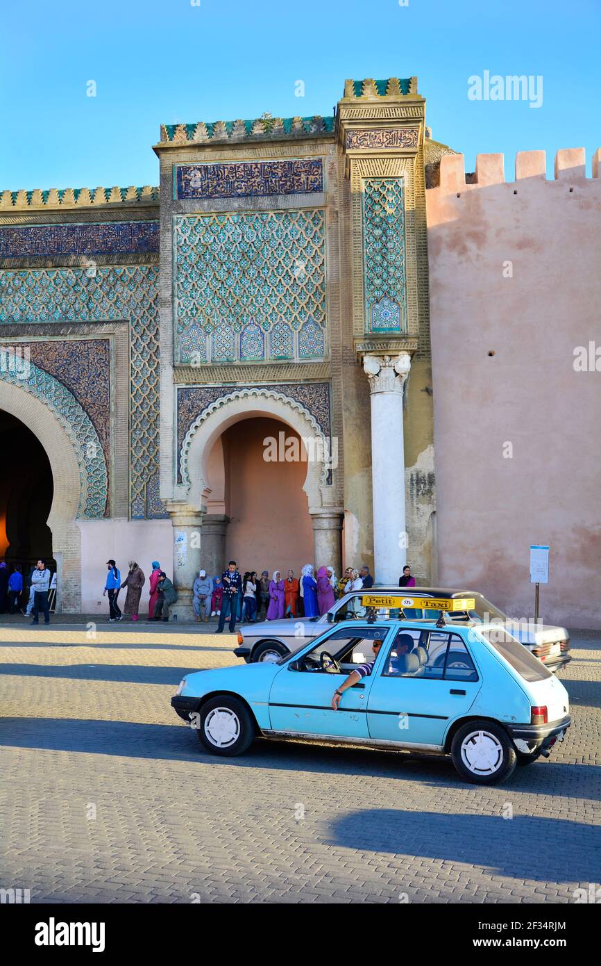 Meknes, Morocco - November 19th 2014: Unidentified people in traditional clothes and petit taxi in front of Bab el-Mansour, petit taxis are a preferre Stock Photo