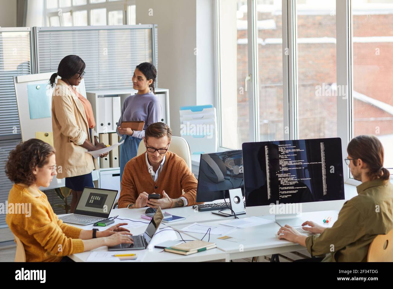 Diverse team of IT developers using computers and programming code ...