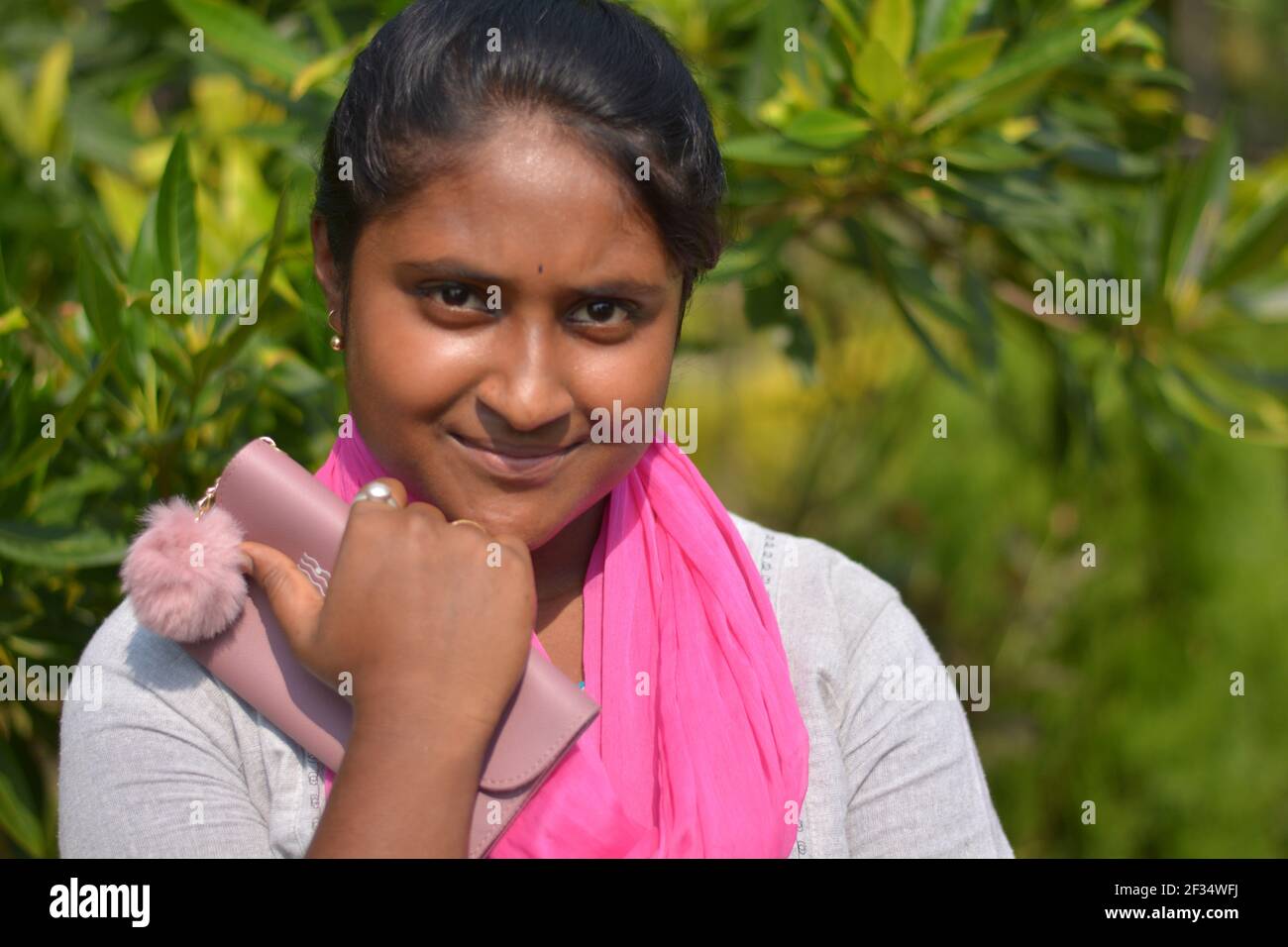 Close up of Indian Bengali teenage girl wearing white cotton salwar with pink dhupatta right hand in front of chin, selective focusing Stock Photo