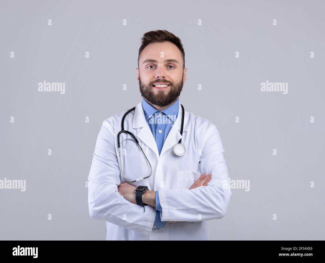 Portrait of positive male doctor posing with crossed arms and smiling ...